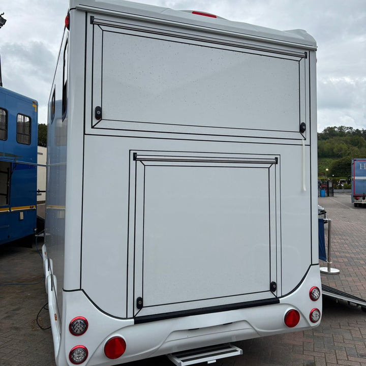 Rear of the trailer with the upper tack-locker hatch and lower loading ramp closed