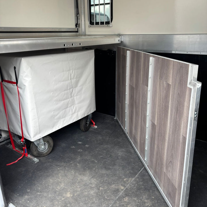 Interior horse area showing the rolling tack chest strapped to the floor beside the wood-effect partition