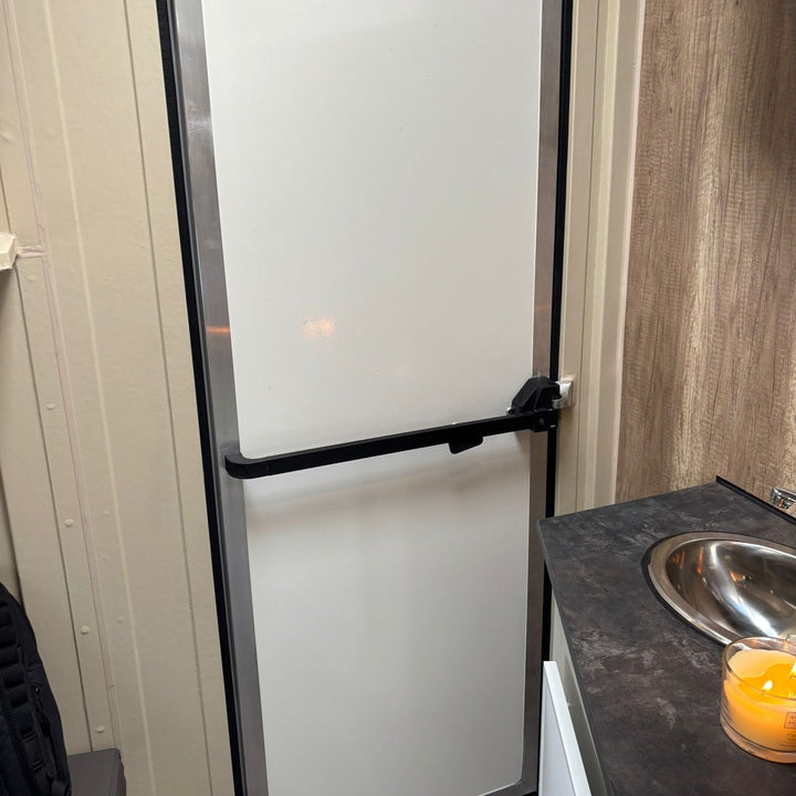 Shower room interior with stainless sink unit and the tall shower cubicle door alongside