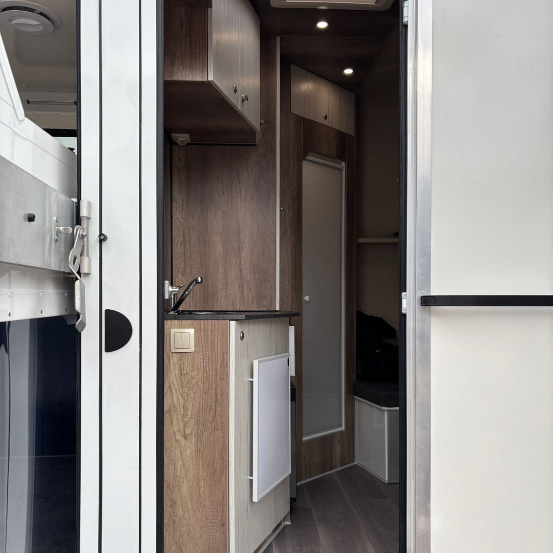 Living area corridor with kitchenette, stainless sink, fridge cupboard and doorway through to the shower room