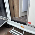 External groom door open with the fold-down step deployed for access into the living area