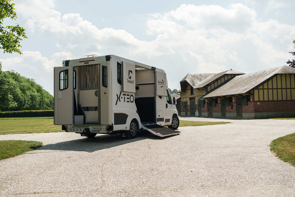 Rear three-quarter view of a Theault XTEO horsebox parked in a stable yard with the ramp closed