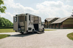 Rear three-quarter view of a Theault XTEO horsebox parked in a stable yard with the ramp closed