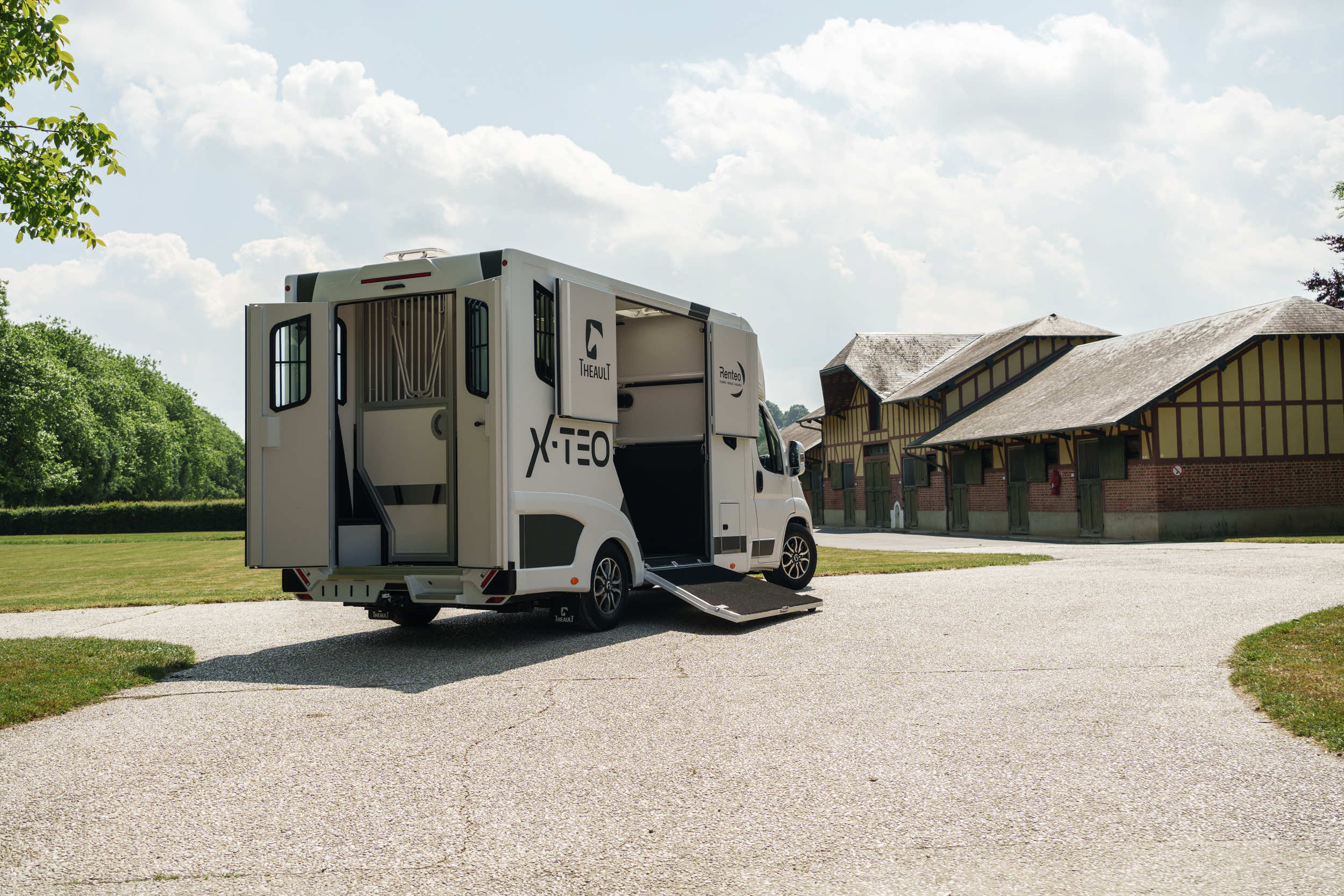 Rear three-quarter view of a Theault XTEO horsebox parked in a stable yard with the ramp closed