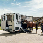 Theault XTEO horsebox with its rear ramp down and two horses being loaded outside a Normandy stable yard