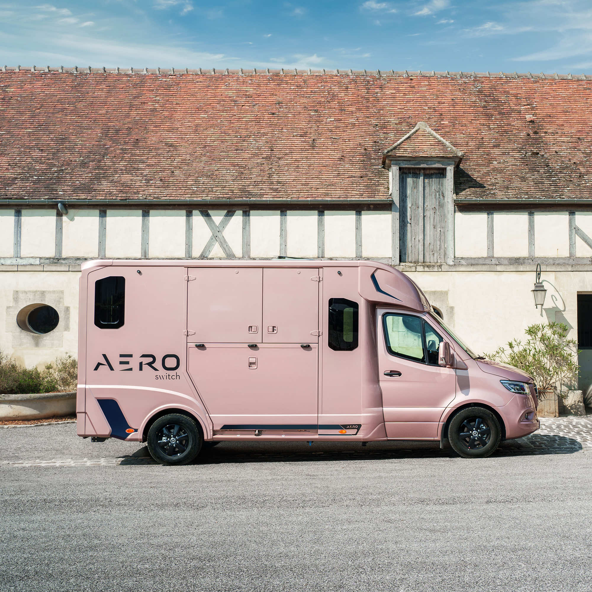 Front three-quarter view of a Theault Aero Sprinter horsebox by a stable