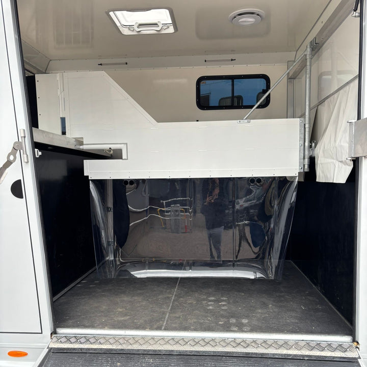 Looking into the horse compartment with the breast bar across the front and clear weather curtain visible