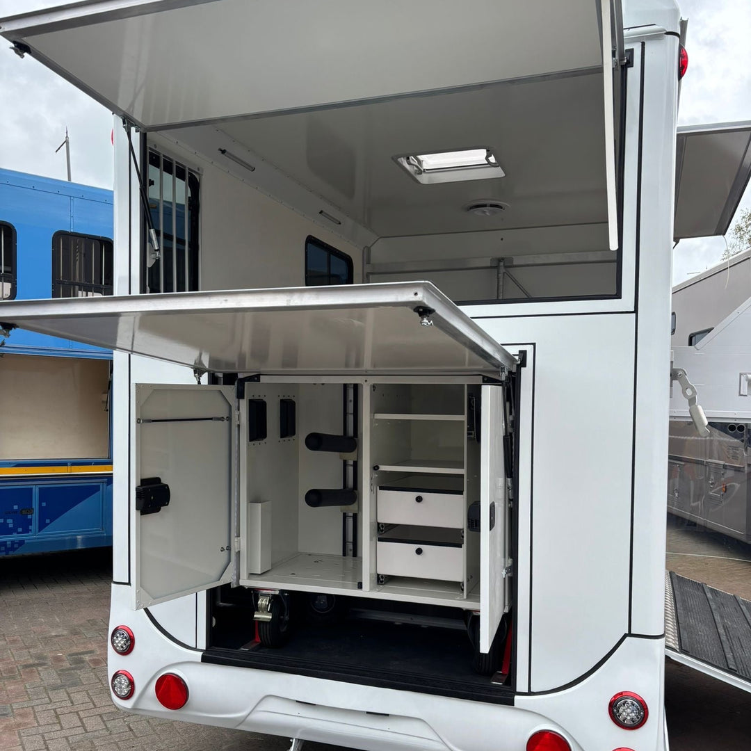 Wide view of the rear tack locker with both upper hatch and lower flap raised, showing organised storage compartments